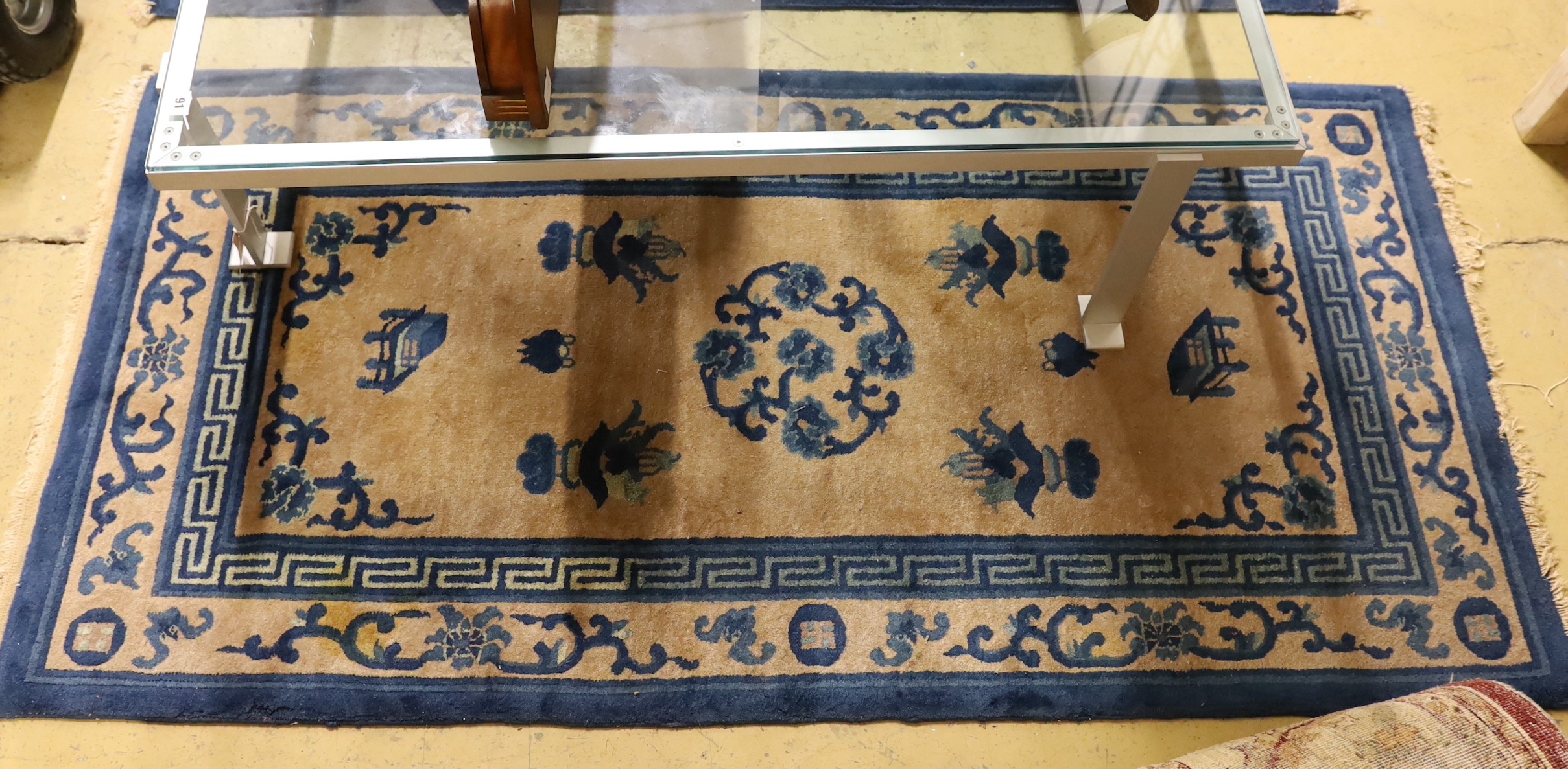 A pair of Chinese beige ground rugs and a similar rug, 174 x 92cm